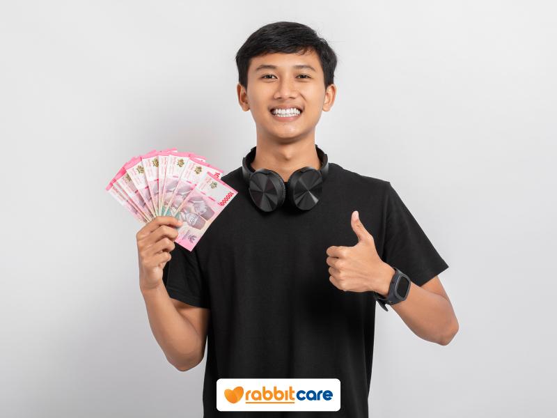 Chàng trai cầm tiền trên tay cười tươi